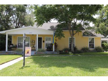 Charming yellow home with a welcoming front porch, mature trees, and a lush green lawn at 13637 13Th St, Dade City, FL 33525