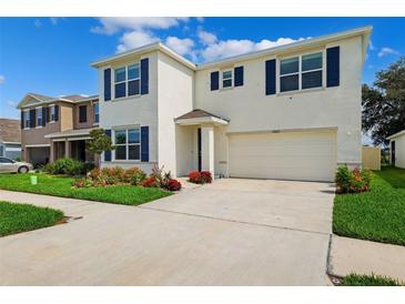 Charming two-story home with blue shutters, white walls, a two-car garage, and well manicured landscaping at 33657 Field Maple Loop, Wesley Chapel, FL 33545
