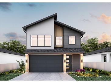 Modern two-story home boasts a sleek dark gray garage door and a stylish front entrance with beautiful landscaping at 12240 Land St, Largo, FL 33773