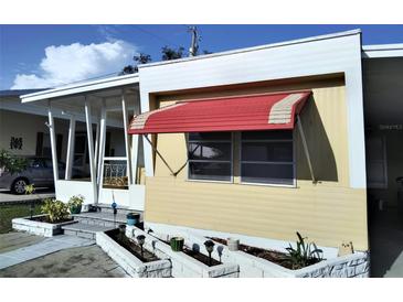 Charming home featuring a small porch, awning, and a well-kept garden area with small plants at 4300 E Bay Dr # 309, Clearwater, FL 33764