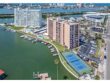 An aerial view featuring a condo building with boat docks, a pool, and a tennis court overlooking a scenic waterway at 51 Island Way # 800, Clearwater Beach, FL 33767
