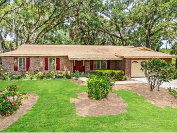 Charming stone home featuring a manicured lawn and vibrant red shutters that add a touch of classic elegance at 616 Pawn Way, Seffner, FL 33584
