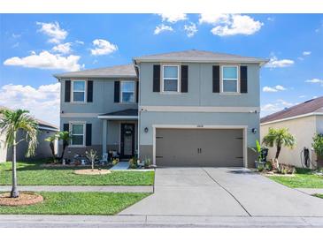 Charming two-story home features a well-manicured lawn and an attached two-car garage at 10624 Aldo Moro Dr, Wimauma, FL 33598