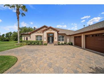 Beautiful home featuring a three-car garage, stone accents, manicured landscaping, and a tile driveway at 11729 Newberry Grove Loop, Riverview, FL 33579