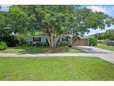 Charming single-story home with blue exterior paint, a well-manicured lawn, mature shade trees, and a two-car garage at 1711 N Highland Ave, Clearwater, FL 33755
