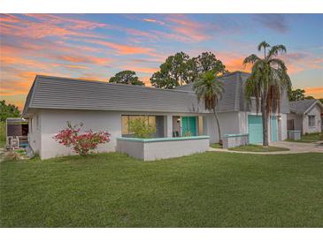 Charming single-Gathering home with a well-manicured lawn, mature landscaping, and a lovely splash of color on the doors at 3519 Richboro Dr, Holiday, FL 34691
