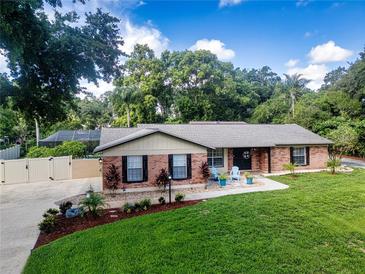 Charming brick home with manicured lawn, lovely landscaping, and inviting front porch with colorful chairs at 4205 Helene Pl, Valrico, FL 33594