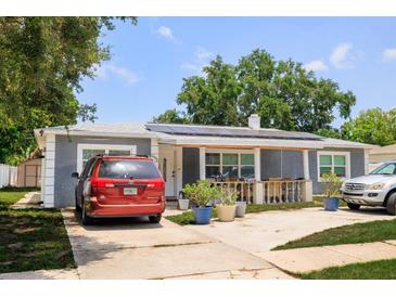 Charming single-story home with a cozy front porch, lush landscaping, and solar panels for energy efficiency at 5895 16Th N St, St Petersburg, FL 33703