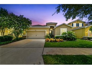 Inviting single-Gathering home featuring a manicured lawn, colorful flowerbeds, and a two-car garage at 6467 Seasound Dr, Apollo Beach, FL 33572