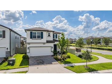 Charming two-story home with brick driveway and manicured lawn at 7517 Notched Pine Bnd, Wesley Chapel, FL 33545