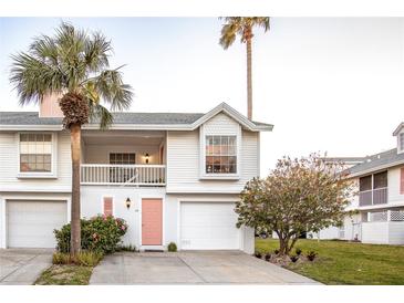 Charming two-story home boasts a pink door, garage, palm trees, and well-maintained landscaping at 112 Sun Isle Cir # 112, Treasure Island, FL 33706