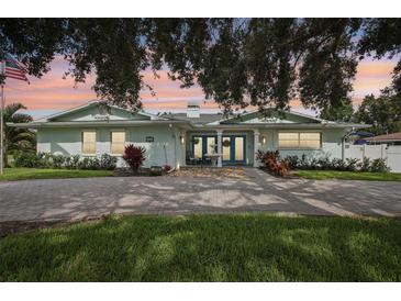 Charming light blue home featuring double doors, a brick driveway and mature landscaping at 316 Cedar Ln, Largo, FL 33770