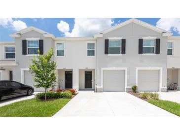 Charming townhomes with well-manicured lawns and attached garages under a cloudy blue sky at 33063 Tulip Petal Ln, Wesley Chapel, FL 33545
