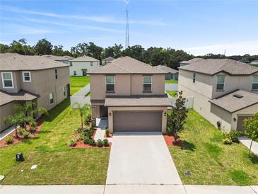 Two-story home featuring a two-car garage, manicured lawn, and tasteful landscaping at 36412 Garden Wall Way, Zephyrhills, FL 33541