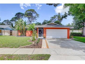 Charming single-story home featuring a lush lawn, vibrant landscaping, and an attached two-car garage at 6865 Circle Creek Dr, Pinellas Park, FL 33781