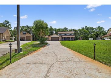 Two story home features a textured driveway, attached garage, and well-manicured lawn at 1357 Dinsmore Ct, New Port Richey, FL 34655