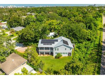 Stunning aerial view of home featuring solar panels and lush greenery in a quiet neighborhood with water views at 321 Barbara Cir, Belleair, FL 33756