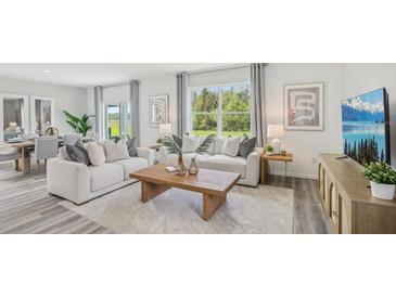 Bright living room with white sofas, a wooden coffee table, and large windows at 35887 Sunflower Hill Dr, Zephyrhills, FL 33541