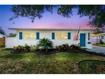 Charming single-story home with vibrant blue shutters and door, complemented by a manicured front yard at 1529 Essex N Dr, St Petersburg, FL 33710