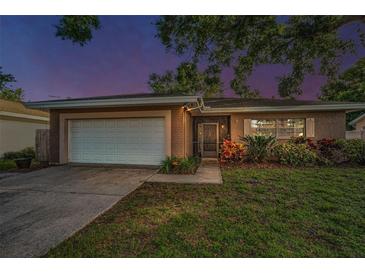 Charming single-story home featuring an attached garage, well-maintained lawn, and beautiful landscaping at 2010 Groveland Rd, Palm Harbor, FL 34683