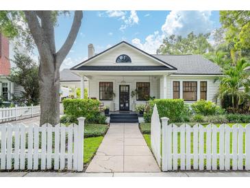 Charming two-story home featuring a classic white picket fence, lush landscaping, and a welcoming front porch at 2412 W Prospect Rd, Tampa, FL 33629