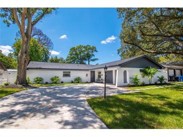 Charming single-story home with a circular driveway, manicured lawn, and lush landscaping at 8010 W Hiawatha St, Tampa, FL 33615