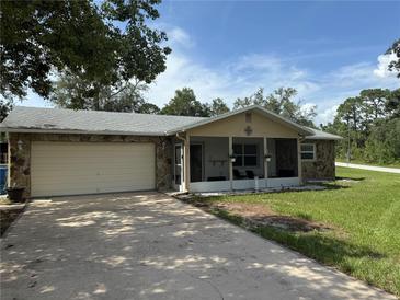 Close-up of a cozy home featuring stone siding, an attached garage, and a welcoming screened front porch at 9171 Vicksburg Rd, Spring Hill, FL 34608