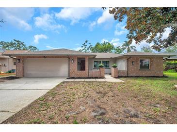 Charming single-story brick home featuring a spacious driveway and attached two-car garage at 1363 Cottage Grove Rd, Tarpon Springs, FL 34689