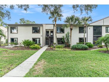 Inviting two-story condo with charming exterior, lush landscaping, and sidewalk leading to the entrance at 326 Moorings Cove Dr # 2B, Tarpon Springs, FL 34689