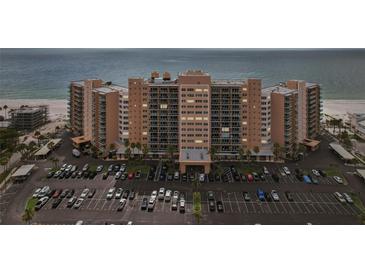 Wide shot of a beachfront condo building, parking lot, and sandy beach at 880 Mandalay Ave # C513, Clearwater Beach, FL 33767