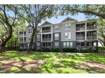 Charming condo building with screened-in porches surrounded by lush green lawns and mature trees at 1201 High Hammock Dr # 302, Tampa, FL 33619