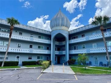 Low-angle view of the exterior of a light blue complex with palm trees, balconies and a central dome at 2341 Haitian Dr # 49, Clearwater, FL 33763