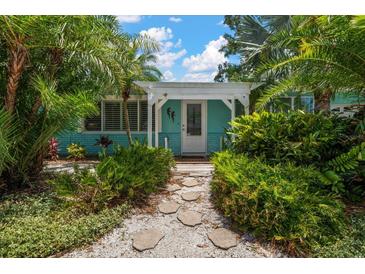 Charming home entrance surrounded by lush tropical landscaping and a welcoming covered porch at 301 Cevera Dr, Dunedin, FL 34698