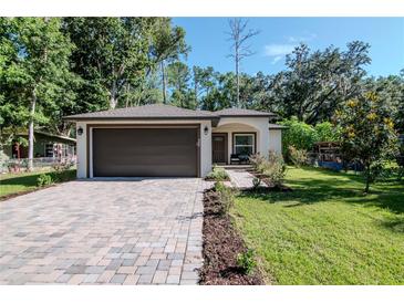 Charming single-story home featuring a brick driveway, a well-kept lawn and a two-car garage at 604 Kinnear Dr, Brooksville, FL 34601