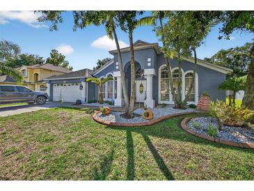 Charming home showcasing the landscaped front yard with beautiful columns and a two-car garage at 9220 Hidden Water Cir, Riverview, FL 33578