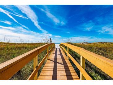 Wooden boardwalk leads to a white sandy beach under a bright blue sky at 12000 Gulf Blvd # 506N, Treasure Island, FL 33706