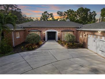 Charming brick home featuring a wide driveway, manicured landscaping, and a welcoming front entrance at 302 Eastleigh Dr, Belleair, FL 33756