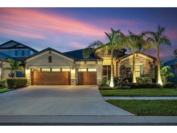 Charming home featuring a manicured lawn and a three-car garage, beautifully illuminated at dusk at 14514 Woodland Spur Dr, Lithia, FL 33547