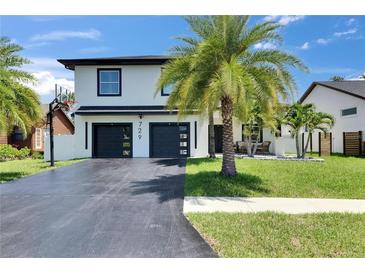 Charming two-story home with a lush front yard, modern garage doors, and a basketball hoop on the driveway at 729 89Th N Ave, St Petersburg, FL 33702