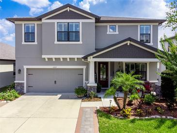 Two-story home featuring a well-manicured lawn, a two-car garage, and a welcoming front porch at 11219 Paddock Manor Ave, Riverview, FL 33569