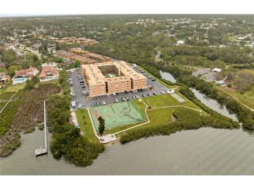 Scenic aerial view of waterfront condo community with tennis courts, a pier and lush greenery at 12760 Indian Rocks Rd # 1049, Largo, FL 33774