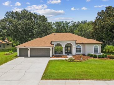 A home boasts a well-manicured lawn, lovely landscaping, and a three car garage at 18803 Misty Shores Ln, Lutz, FL 33548