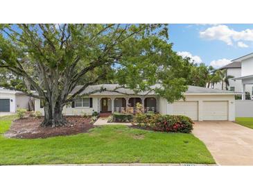 Charming single-story home with a well-manicured lawn, mature tree, and two-car garage at 3108 S Omar Ave, Tampa, FL 33629
