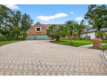 Charming brick home featuring a paved driveway, lush lawn, and mature trees under a sunny sky at 3269 Nicks Pl, Clearwater, FL 33761