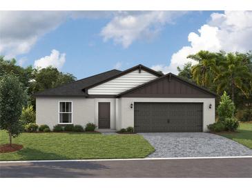 Charming single-story home with a well-manicured lawn and an attached two-car garage, under a cloudy blue sky at 36915 Sagemoor Dr, Zephyrhills, FL 33541
