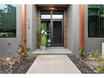 Modern home's front entrance showcases a sleek design with a glass door and contemporary landscaping at 4148 Gauge Line Loop, Tampa, FL 33624