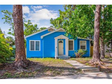 Bright blue bungalow with white trim, complemented by mature trees and a welcoming front porch at 4411 3Rd S Ave, St Petersburg, FL 33711