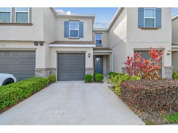 Charming townhome featuring a well-maintained lawn, a one-car garage, and stylish gray and blue accents at 6825 Citrus Creek Ln, Tampa, FL 33625