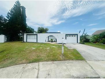 Charming home featuring a white exterior, arched entryway, and well-manicured lawn at 3516 Norland Ct, Holiday, FL 34691