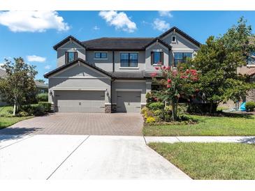 Stunning two-story home featuring a three-car garage, well-manicured landscaping, and a brick driveway at 3477 Barbour Trl, Odessa, FL 33556